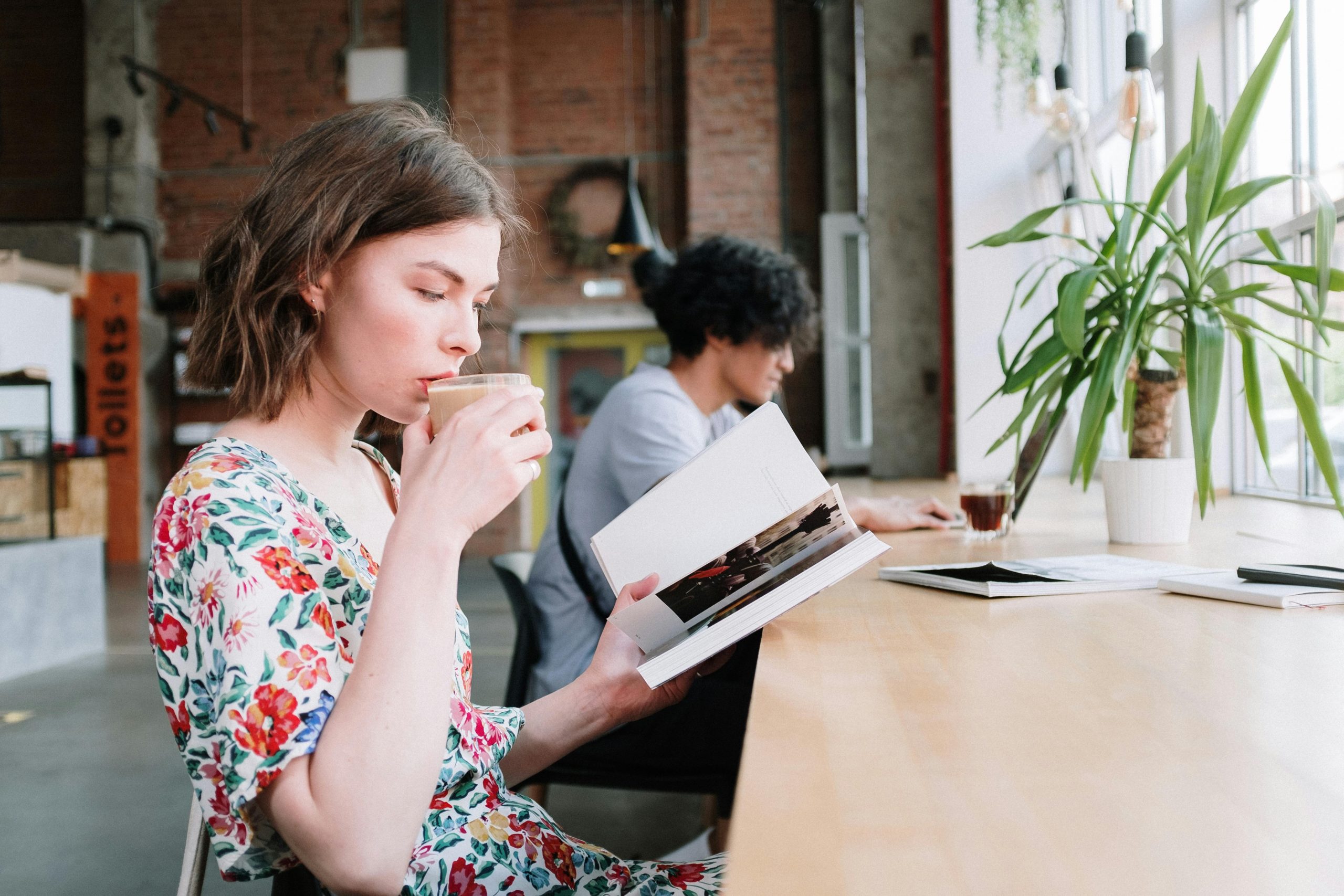 Woman reading a book and drinking coffee in a calm, creative workspace, representing marketing and branding for authors and writers